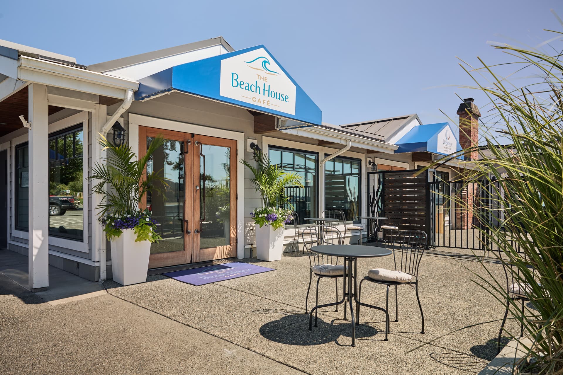 The Beach House Café welcoming entrance with outdoor seating and tropical plants