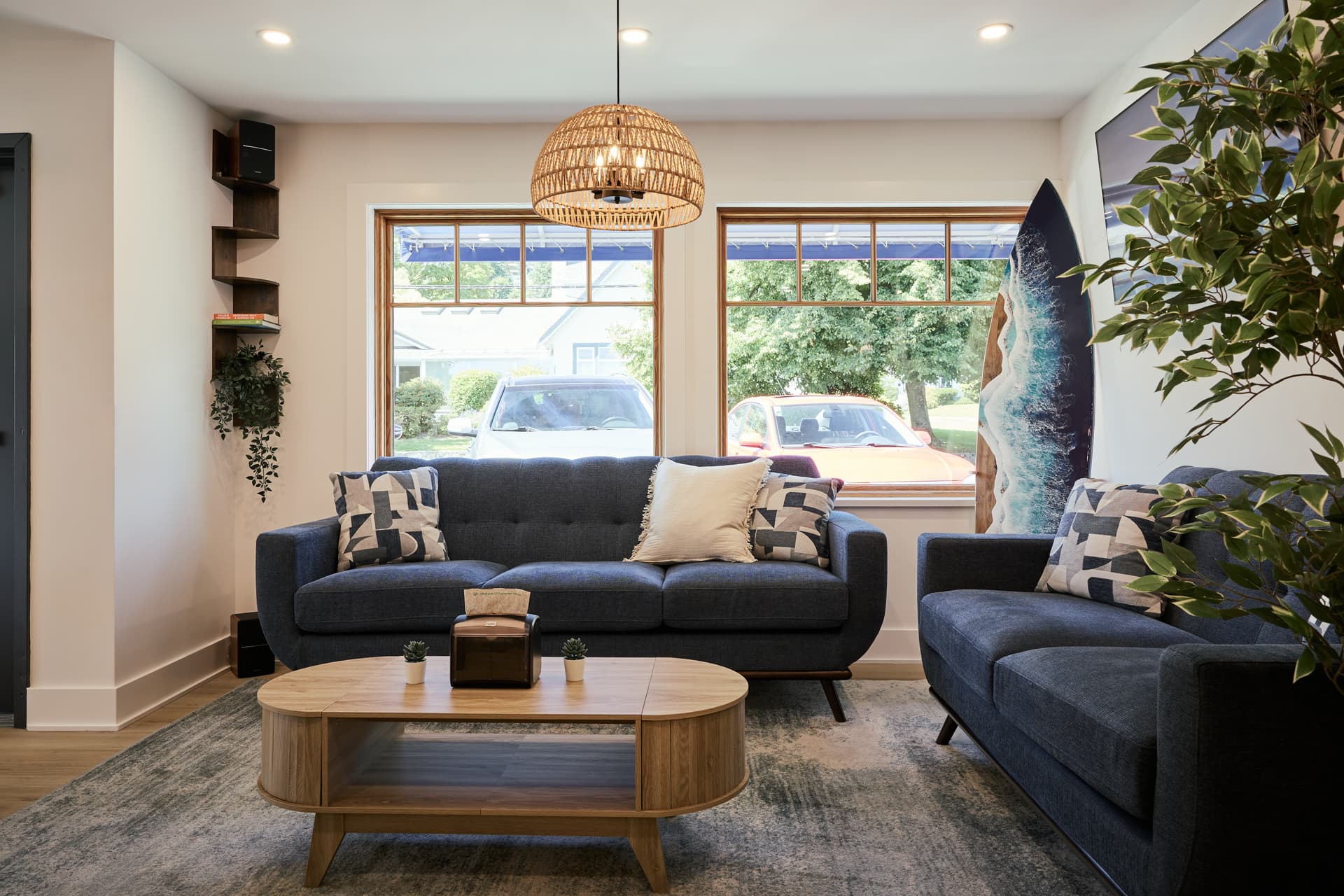 Relaxed coastal lounge with navy blue sofas and rattan pendant lights